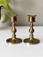 Front view of a pair of vintage solid brass candlesticks showing shape and patina.