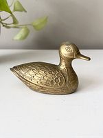 Side angled view of vintage brass duck showing detailed etched feather and body patterns.