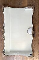 Full view of vintage large mirror, showing curved edges and ornate brass corners.