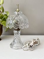 Front view of the vintage cut glass lamp with electric cord coiled beside it.