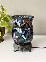 Photo showing the stained glass mosaic lamp with floral pattern on the brass base, front and side views visible.