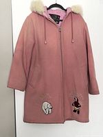 Front view of pink winter parka with fur-trimmed hood and embroidery, hung on black hanger against white background.