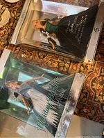 Two boxed Holiday Barbie dolls from 2004 and 2005 editions with packaging showing water damage.