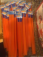 Forty 24-inch orange straight track pieces arranged in bundles with their original Hot Wheels packaging including blue connector handles visible.