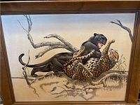 Full view of the silk screen artwork showing a black panther attacking a spotted panther on a grassy terrain with bare branches.