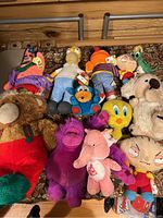 Overview of 12 stuffed animals from various cartoons and characters lying together showing colors and sizes