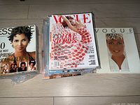 Pile of magazines including an Essence cover with a portrait of a woman and a Vogue Complete Beauty book.