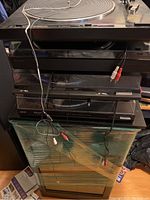 Stack of four vintage vinyl record players showing their fronts and attached cables