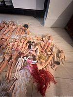 Close-up angled view showing detailed condition of the dolls, revealing some with missing or tangled hair and discoloration, emphasizing rough shape and need for cleaning.