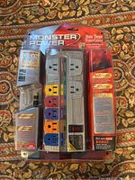 Clear front view of Monster Power Home Theatre PowerCenter HT700 8 outlet surge protector in original sealed packaging showing the unit and coaxial cable adapter.