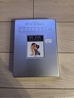 Silver metal tin case with embossed Walt Disney Treasures branding and front label with Dr Syn DVD cover art