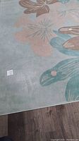 Image showing part of the floral patterned area rug on wooden floor, displaying the colors and floral design detail.