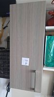 Front view of the wood finish rectangular bathroom cabinet with horizontal metal handle and Cutler brand sticker on front