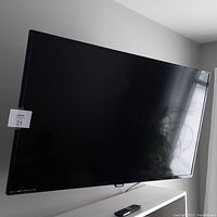 Philips 43 inch TV mounted on wall showing the screen and remote placed on flat surface below it.