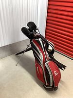 Front angle of red, silver and black Nike stand golf bag with clubs and head covers