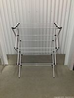 Front view of metal drying rack fully open showing horizontal rods and frame structure.