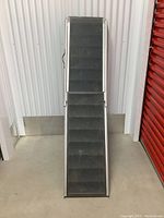 Full view of the portable steel ramp showing two sections extended and resting on the ground.