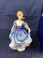 Photo capturing the full front view of the Royal Doulton figurine showing its posture, the slightly lifted skirt, and color gradient on the dress.