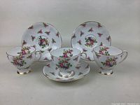 Three Royal Standard fine bone china tea cups with matching saucers, rose floral pattern, displayed side by side on a neutral background.