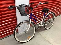 Full front-left view of blue and white Schwinn cruiser bicycle showing frame, wheels and saddle