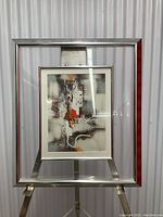 Full view of the framed signed abstract art print on a metal stand, showing the entire artwork and frame.