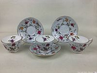Full set of 3 tea cups and 3 matching saucers arranged together showing floral and bird pattern with gold trim.