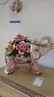 Porcelain elephant figurine with floral arrangement on back, showing overall design and measurements.