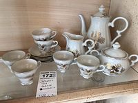 Complete Japanese Tea set displayed, includes coffee/tea pot, sugar bowl, milk jug, six cups, and six saucers with ornate gold and black leaf designs.