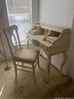 Desk and chair set shown near window with natural lighting, highlighting size and condition of the desk and chair.