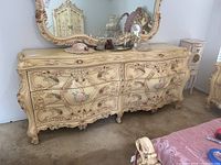 Front view of large cream ornate dresser with matching mirror and floral hand-painted details.