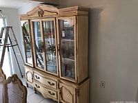 Front view of Bassett French Provincial buffet cabinet showing four glass doors, two drawers, two side cabinets, and carved crown molding.