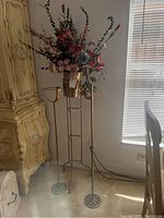 View of the three metal floor vase holders with silk flower arrangements showing size variation and general appearance.