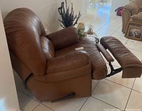 Side view of the brown leather recliner chair showing manual lever and footrest extended.