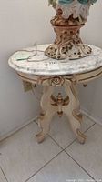 Full view of the carved wood table showing marble top and ornate base.