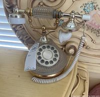 Full view of vintage rotary phone with glass body and metal handset cradle