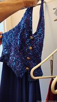 Blue gown hanging, showing top bodice with sequins and gold buttons detail.