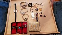 Overview of all items including two watches, rings in red-lined tray, keychains, and Cub Scout case