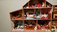 Full view of the 8-room wooden doll house with miniature furnishings in bedrooms, living and dining areas.