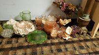 Full overview of lot items including green and pink glassware arranged on a wooden surface with paper packing material.