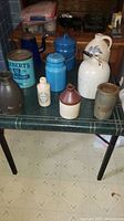 Overview of nine assorted jugs, tins and canisters on folding table