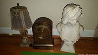 Overview showing all three items: mantle clock, bust sculpture, and small lamp.
