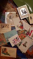 Spread-out assortment of old postcards and greeting cards showing different styles and artwork