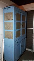 Full side and front view of the blue painted pie safe showing four embossed tin doors and one drawer.