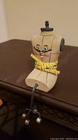 Mannekin figure with measuring tape sitting on shelf edge