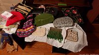 Overview of all items including purses, travel bags, scarves, and handkerchiefs spread on floor and covered in white tissue paper.