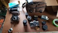 Full overview of the camera kit items including Canon AV-1 camera body, lenses, teleconverters, flash, bag, and other accessories on a wooden surface.