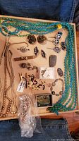Full view of tray showing turquoise bead necklaces, pearl-like beads, earrings, pins, and vintage zipper pulls including animal shapes.