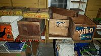 Photo of eight vintage wooden crates on a table showing Coca-Cola, Blue Goose, and Dahn-D logos among plain crates
