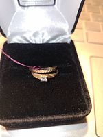 Photo of two small 10kt gold rings placed together inside a black velvet ring box with silver satin interior lining.