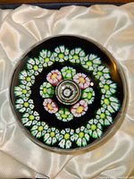 Top view showing the circular millefiori floral cane patterns and central bubble with Caithness Glass marked cane inside the spherical glass paperweight.